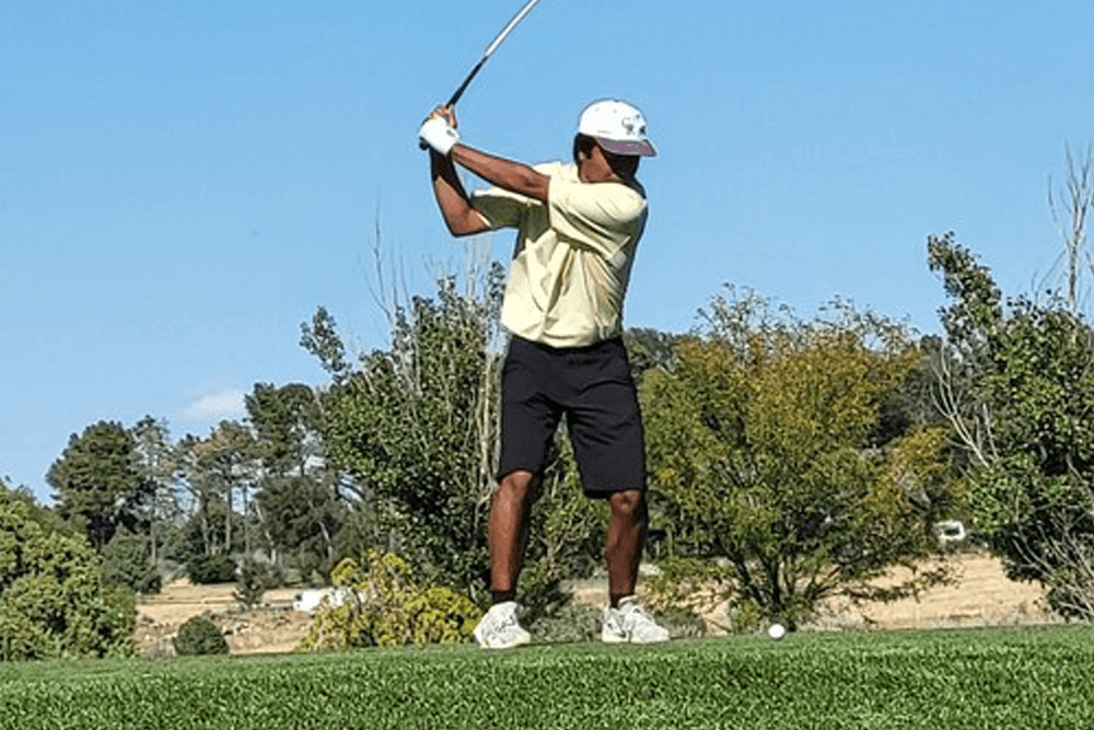 A golfer prepares to swing on a sunny day.