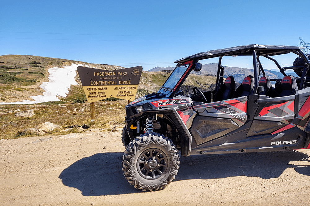 A Polaris side-by-side vehicle parked next to a sign for Hagerman Pass, marking the Continental Divide.