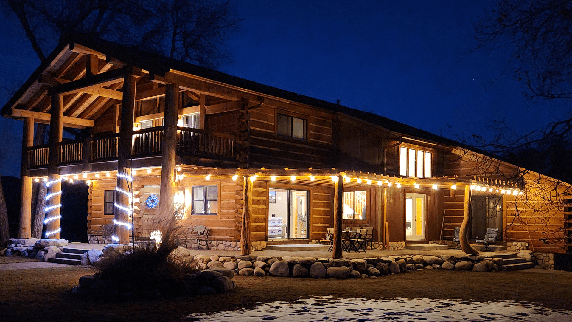 A log cabin illuminated with festive lights at night.